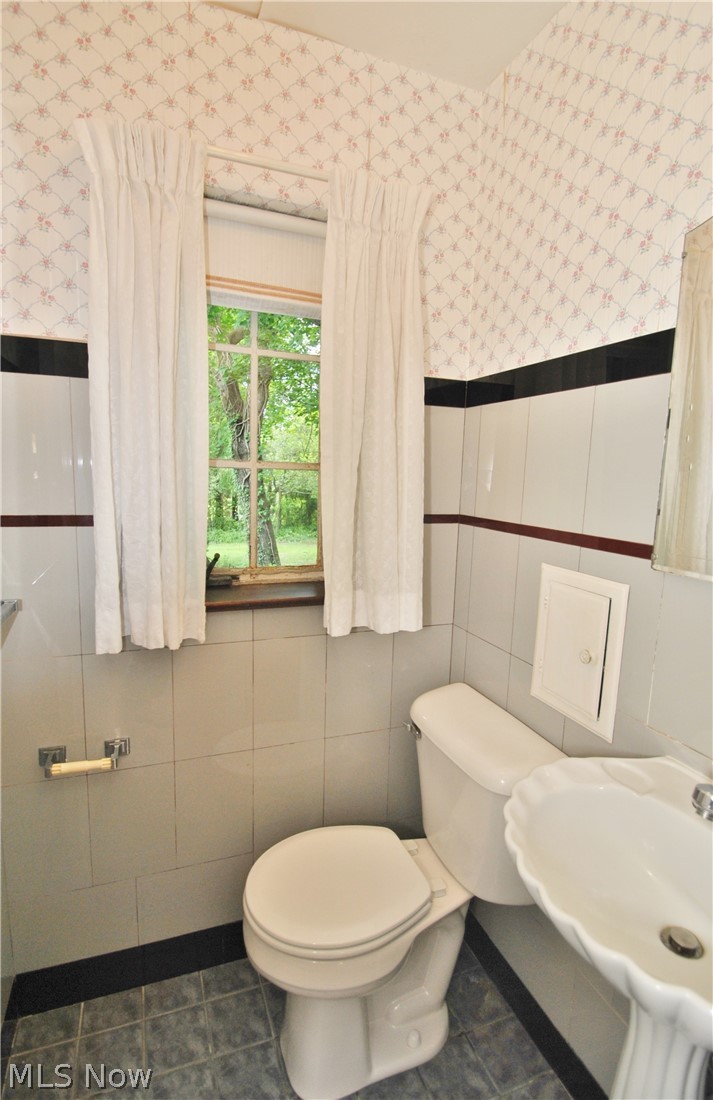 187 Durward Road Akron, OH 44313 - Photo 10 of 21 First floor guest bath has vitrolite walls, pedestal sink and original mirrored vanity area leading into the half bath.