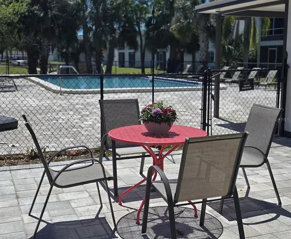 a patio with table and chairs and potted plants