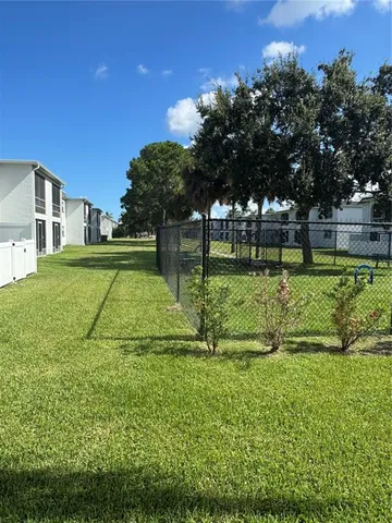 a view of a house with a big yard and potted plants and large trees