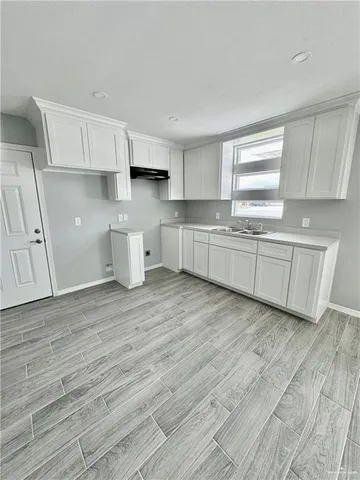 a kitchen with cabinets wooden floor and a window