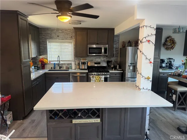 a kitchen with a stove a refrigerator a sink a dining table and chairs with wooden floor