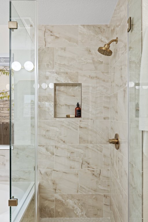1305 Tudor House Road Pflugerville, TX 78660 - Photo 25 of 40 The walk-in shower features oversized tile, a built-in niche, and a modern glass enclosure for a polished, spa-inspired feel.