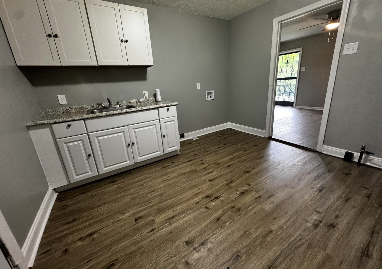 2059 Rile Street Memphis, TN 38109 - Photo 2 of 5 a kitchen with granite countertop white cabinets and wooden floor