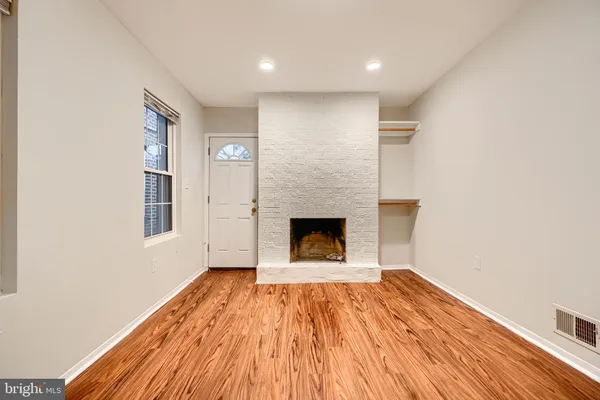 a view of a livingroom with wooden floor and a fireplace