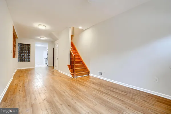 a view of an empty room with wooden floor and stairs
