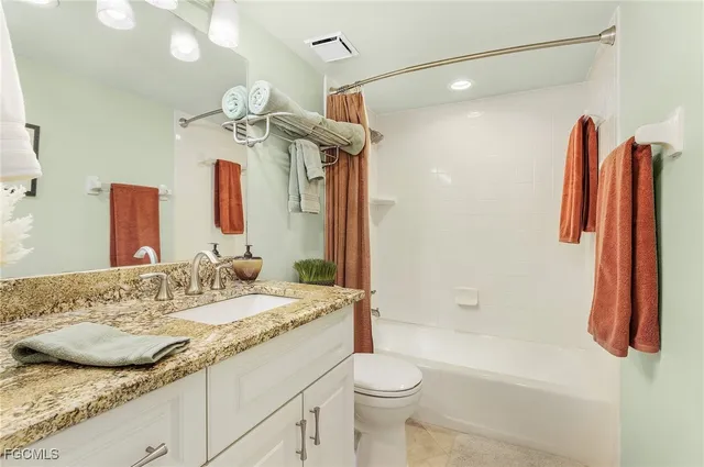 a bathroom with a granite countertop sink a toilet and shower