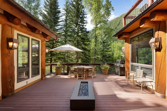 a view of a patio with table and chairs potted plants with wooden floor and fence