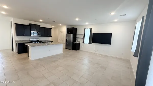 a kitchen with stainless steel appliances kitchen island granite countertop a refrigerator and a stove top oven