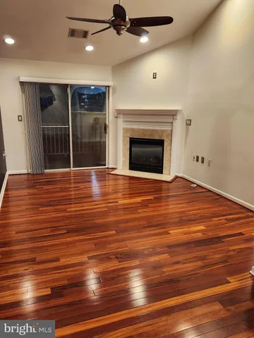 a view of an empty room with a fireplace and a ceiling fan