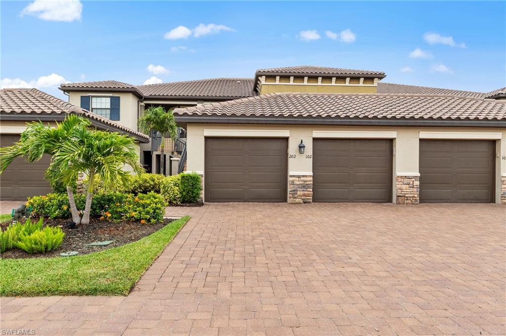 9366 Pocida Court, Unit 202 Naples, FL 34119 - Photo 2 of 44 a front view of a house with a yard and garage