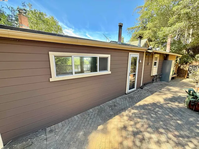 a view of a patio with table and chairs under an umbrella with large trees