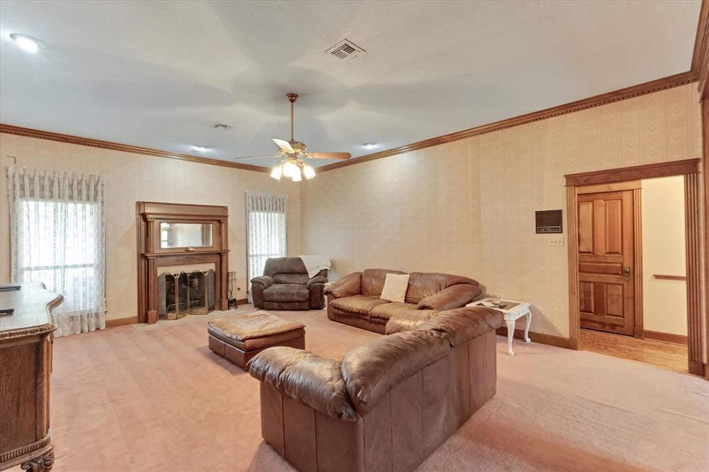 2717 Clear Lake Road Weatherford, TX 76087 - Photo 3 of 40 Spacious living area featuring a wood-mantled fireplace with an integrated mirror, two windows, and a ceiling fan
