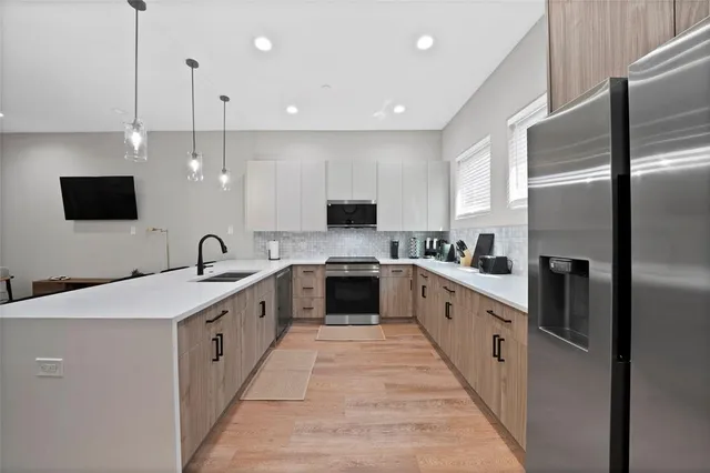 a large kitchen with stainless steel appliances kitchen island a large counter top a sink a stove and a refrigerator