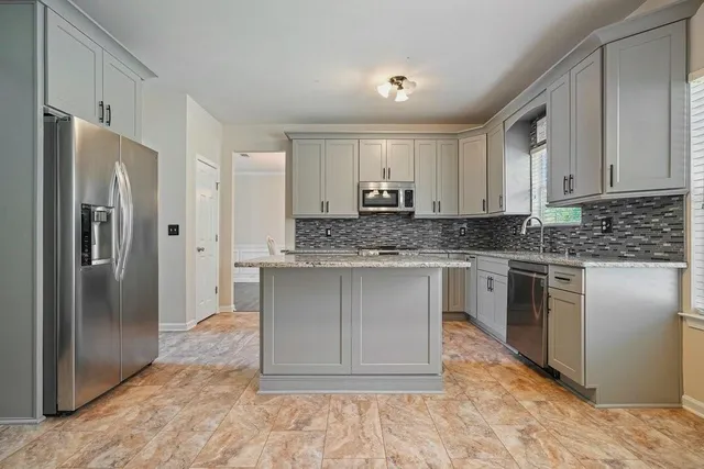 a kitchen with granite countertop a stove a sink dishwasher a refrigerator and white cabinets with wooden floor