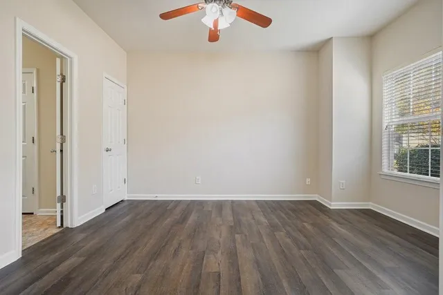 an empty room with wooden floor and ceiling fan