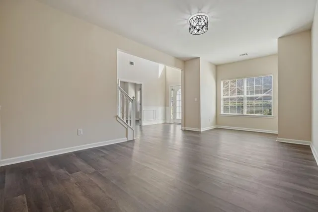 a dining room with wooden floor a chandelier a wooden table and chairs