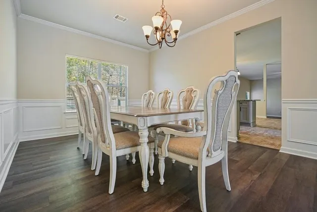 a large kitchen with a stove a sink dishwasher a refrigerator and white cabinets with wooden floor