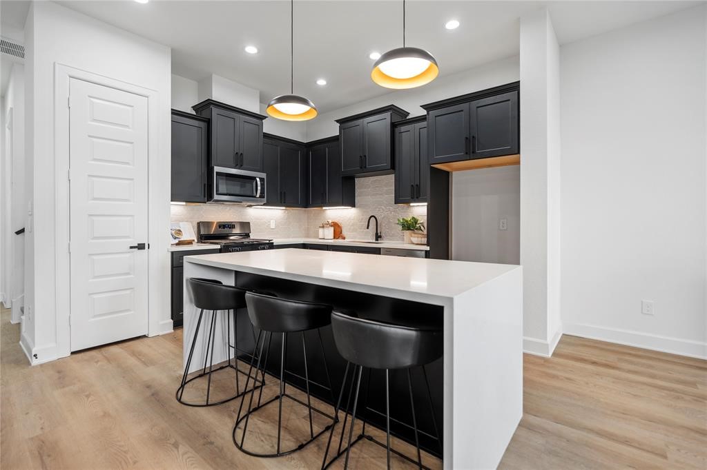 6321 Foster Street Houston, TX 77021 - Photo 3 of 19 Modern kitchen with sleek black cabinets, a spacious island with seating, and stylish pendant lighting, offering a perfect blend of functionality and elegance.