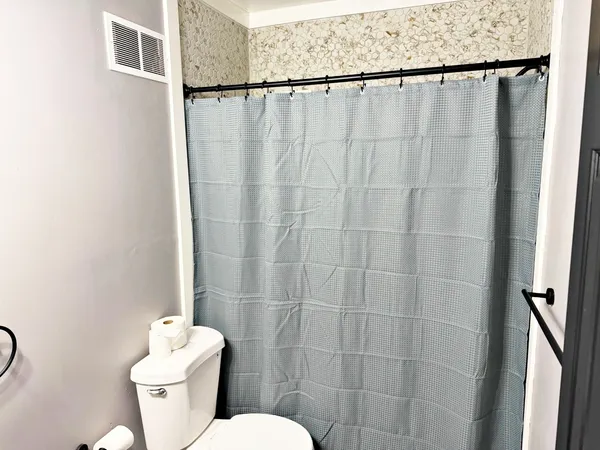 a bathroom with a toilet and a shower curtain