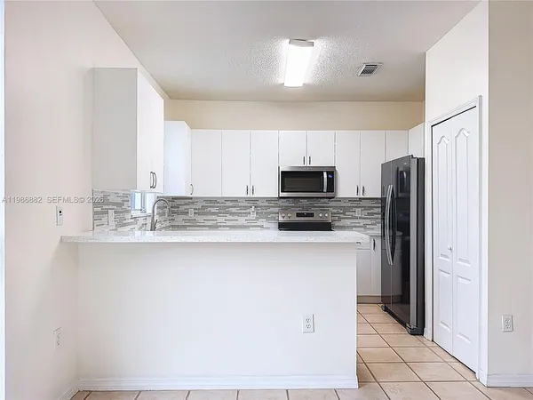 a kitchen with stainless steel appliances a refrigerator sink and microwave