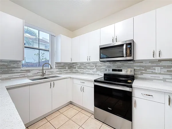 a kitchen with granite countertop a sink cabinets and stainless steel appliances