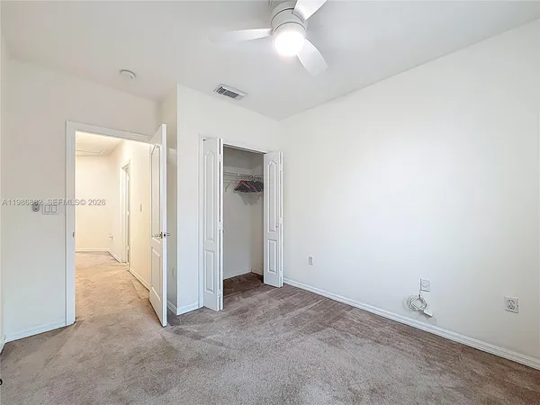 an empty room with closet and a chandelier fan