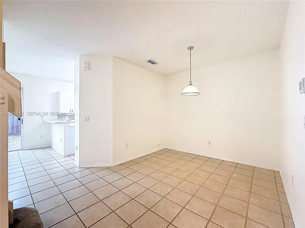 a view of a refrigerator in kitchen and an empty room