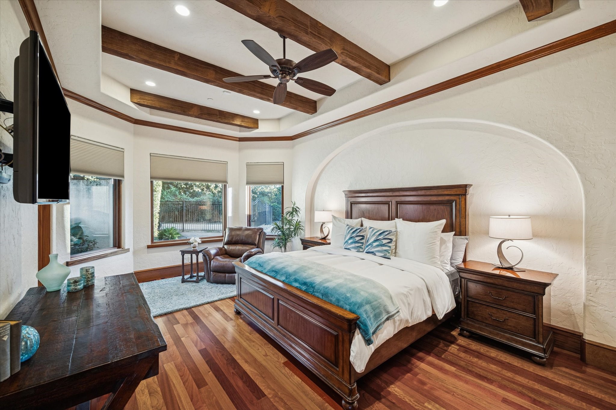 21538 Mueschke Road Tomball, TX 77377 - Photo 33 of 50 Another secondary bedroom on the first level, featuring elegant wood beam accents on the ceiling and a graceful wall arch. It offers direct access to a private en-suite bathroom with similar refined finishes, ensuring comfort and privacy. With multiple beautifully appointed bedrooms on the main level, your loved ones will enjoy convenience, comfort, and a true sense of home.