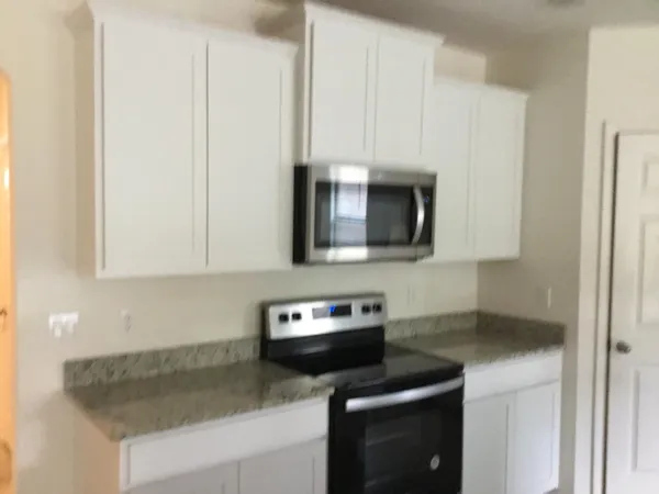 a kitchen with stainless steel appliances granite countertop white cabinets and a stove