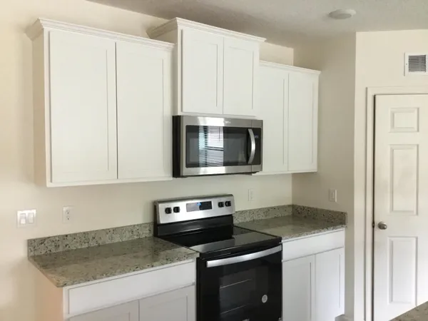 a kitchen with granite countertop white cabinets and stainless steel appliances