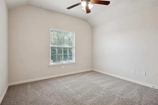 an empty room with a chandelier fan and windows