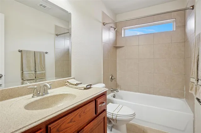 a bathroom with a granite countertop sink a toilet a mirror a bathtub and shower