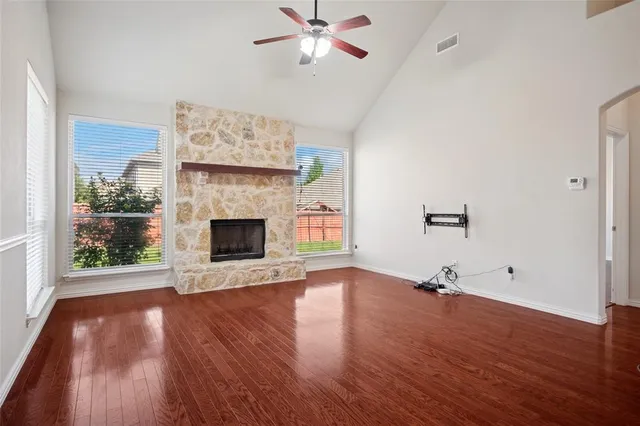 an empty room with wooden floor a fireplace a ceiling fan and a wooden floor