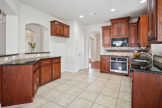 a kitchen with stainless steel appliances granite countertop a stove top oven a sink dishwasher and granite countertops with cabinets