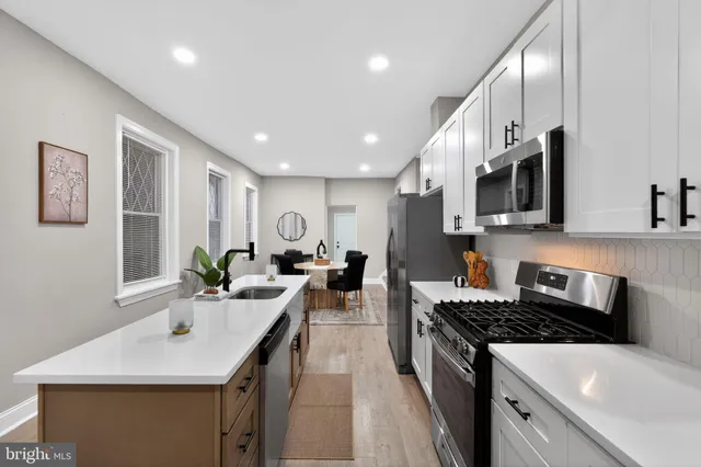 a kitchen with stainless steel appliances a sink a stove top oven a counter space and cabinets