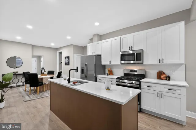 a room with kitchen island a white counter top space a center island stainless steel appliances and cabinets