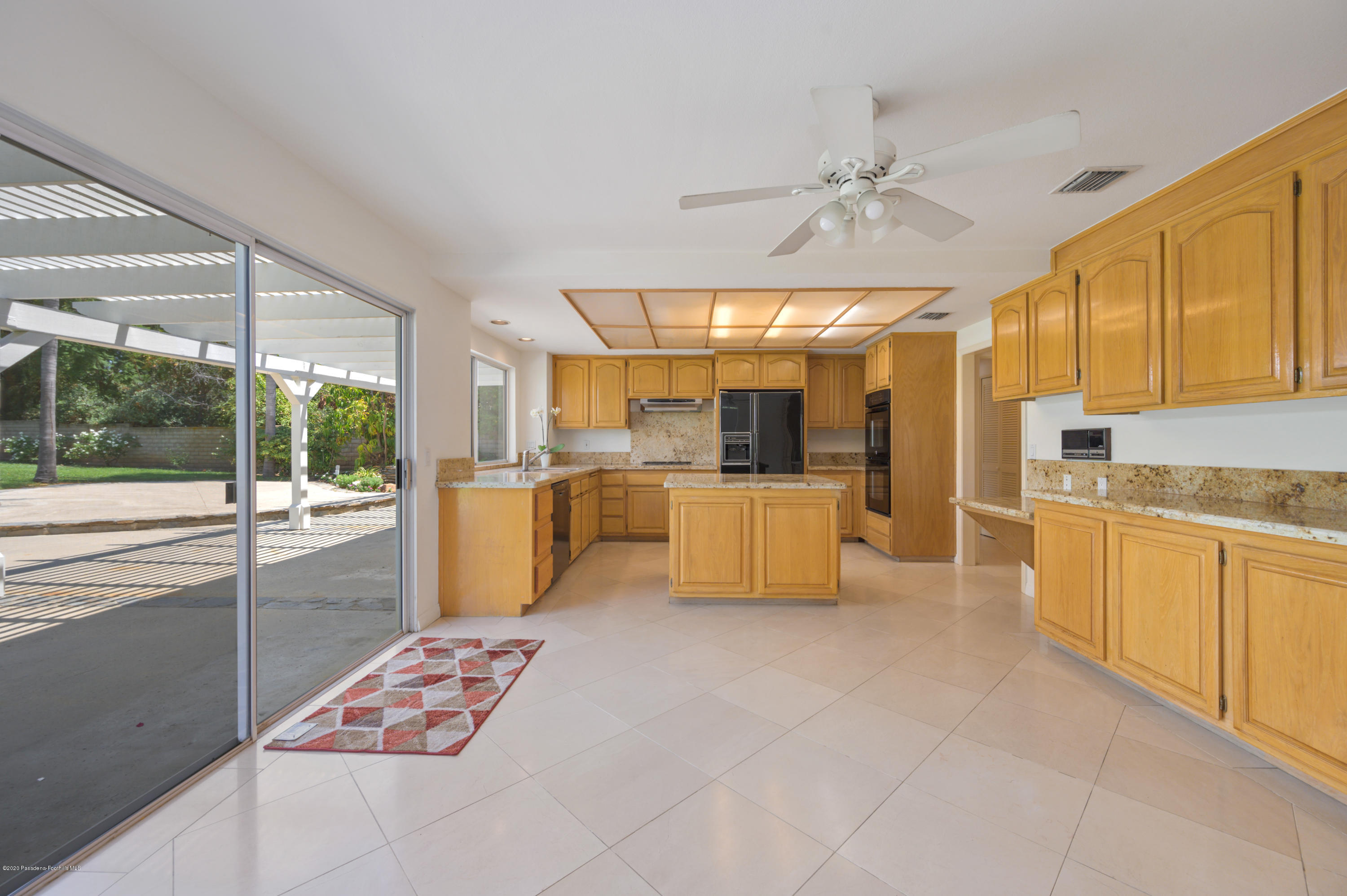 10652 Rathburn Avenue Porter Ranch, CA 91326 - Photo 17 of 61 a large white kitchen with kitchen island a large window cabinets a sink and stainless steel appliances