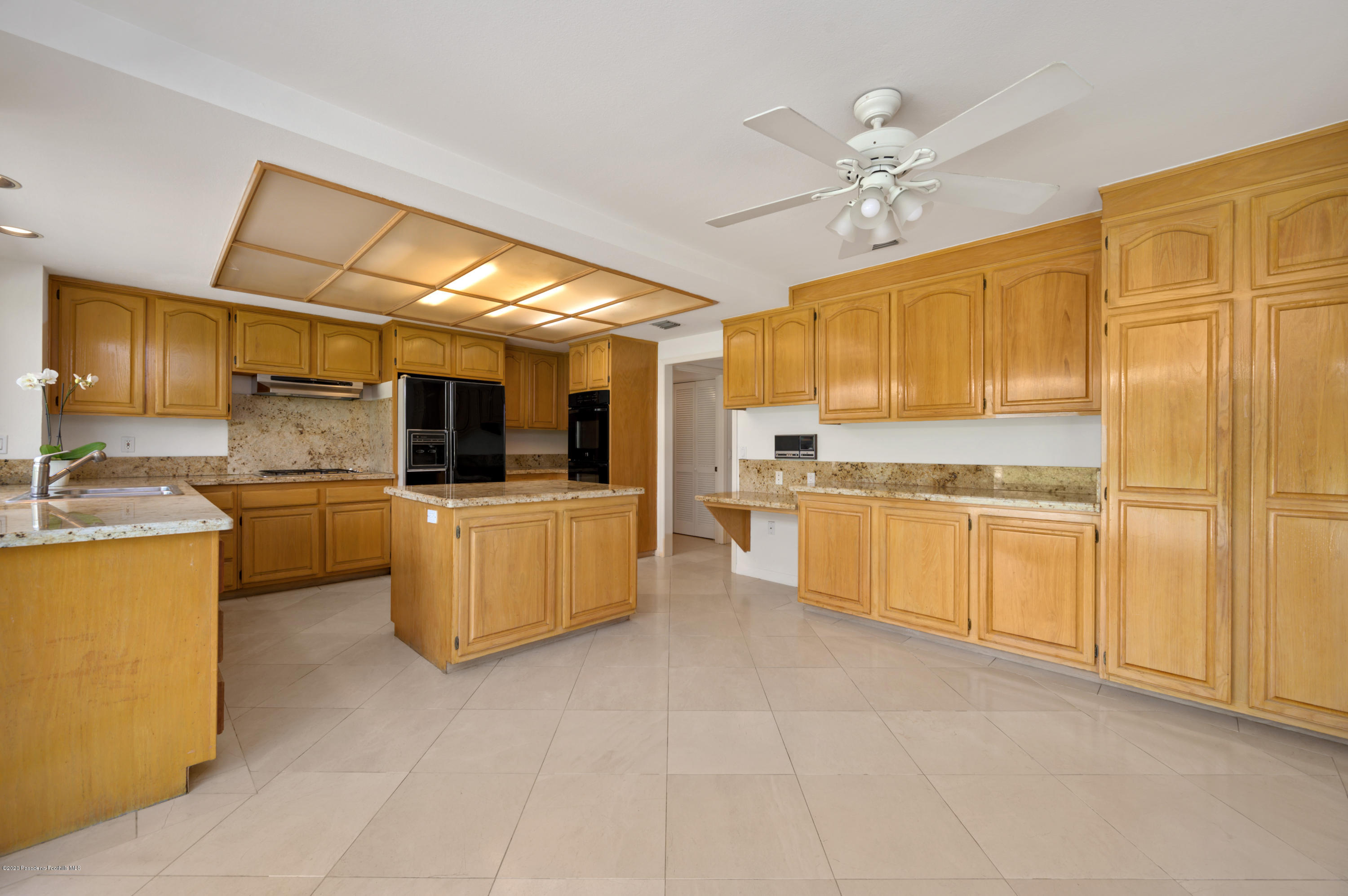 10652 Rathburn Avenue Porter Ranch, CA 91326 - Photo 18 of 61 a kitchen with a refrigerator a stove top oven a sink dishwasher and dining table with wooden floor
