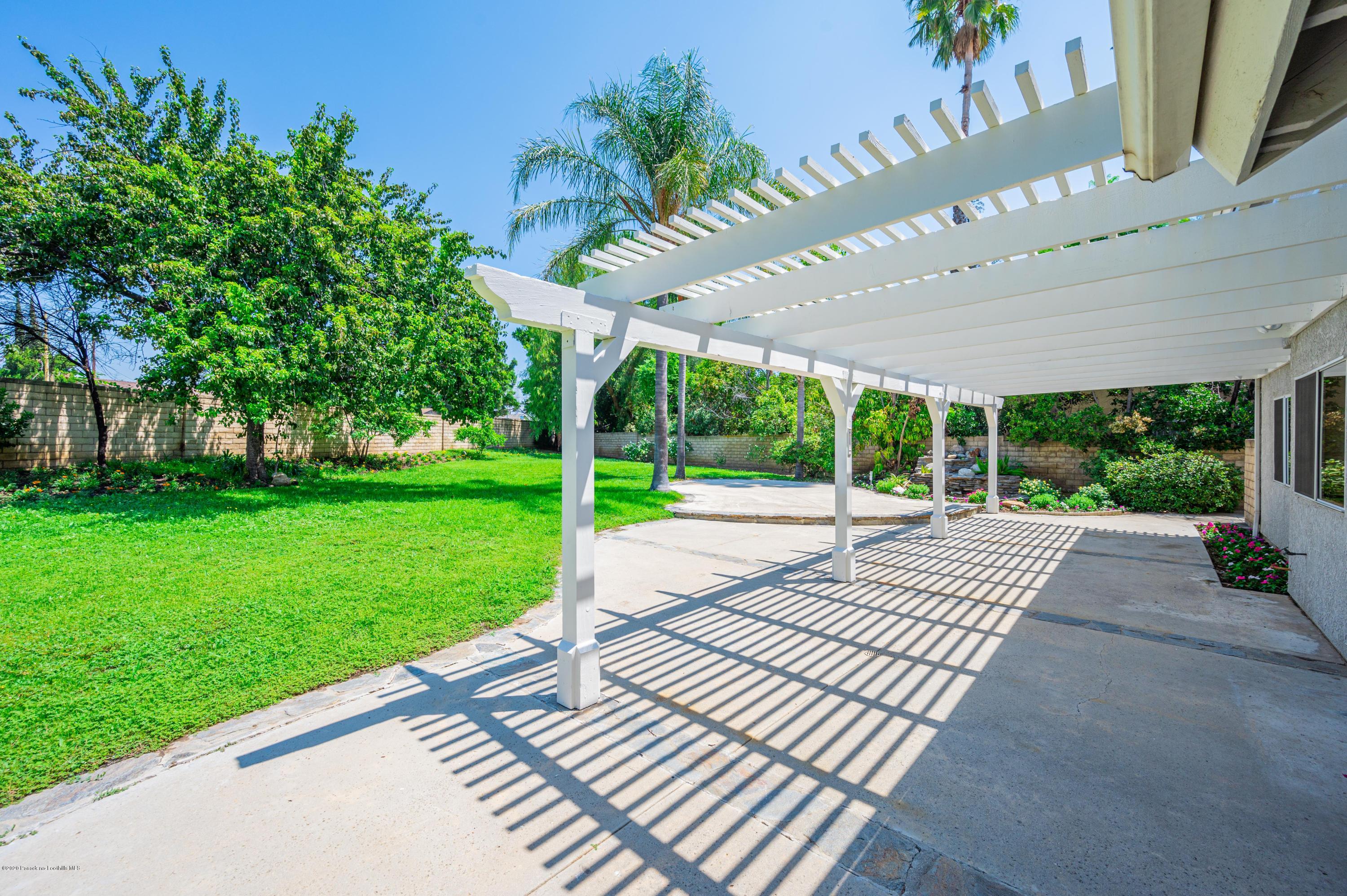 10652 Rathburn Avenue Porter Ranch, CA 91326 - Photo 42 of 61 a view of a patio with a table chairs potted plants and palm trees