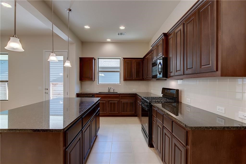 6907 Idea Road Austin, TX 78741 - Photo 8 of 29 Kitchen area with dark cabinets, granite counter tops, and gas stove