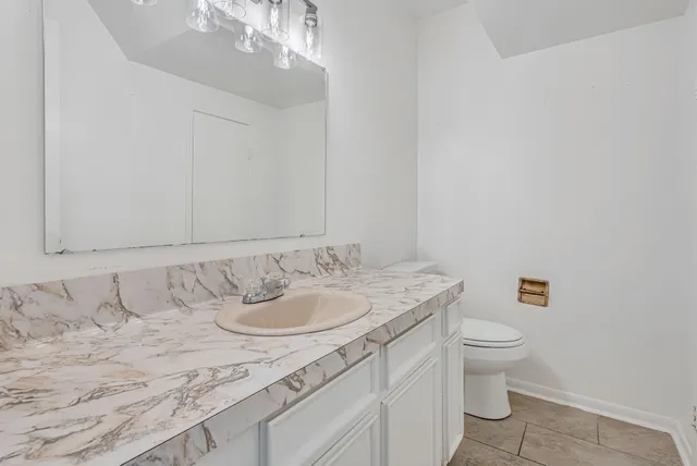 a bathroom with a granite countertop sink and a toilet