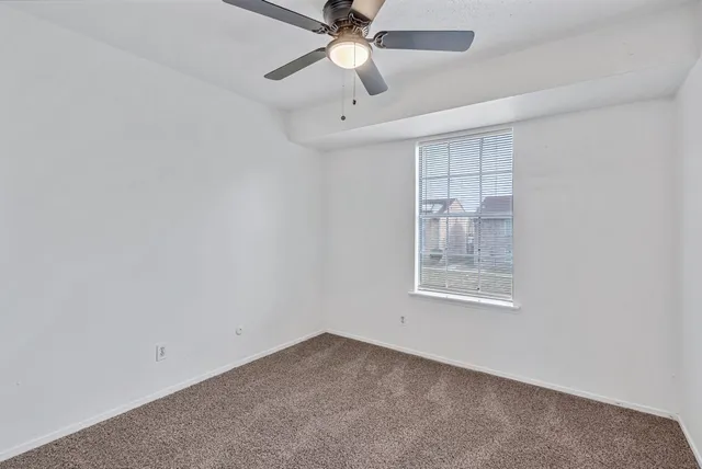 an empty room with a chandelier fan and windows