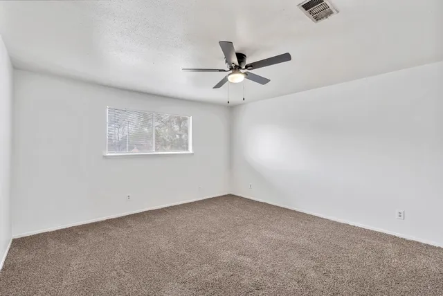 an empty room with a window and a ceiling fan