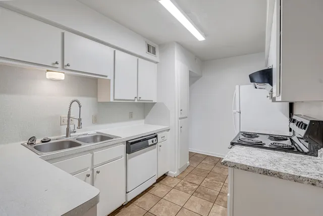 a kitchen with granite countertop a sink stove and cabinets
