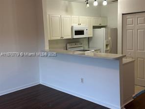 1555 Northeast 33rd Road, Unit 1042 Homestead, FL 33033 - Photo 6 of 19 a kitchen with stainless steel appliances a sink a stove a microwave and white cabinets