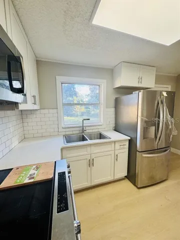 a kitchen with stainless steel appliances granite countertop a sink a stove a refrigerator a washer dryer and white cabinets