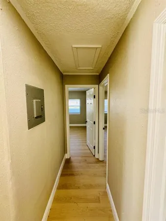 a view of a hallway with wooden floor and a bathroom