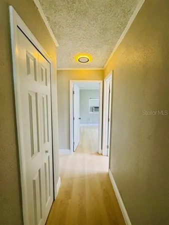 a view of a hallway with wooden floor and a bathroom