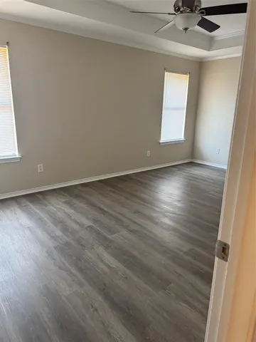 an empty room with wooden floor and windows