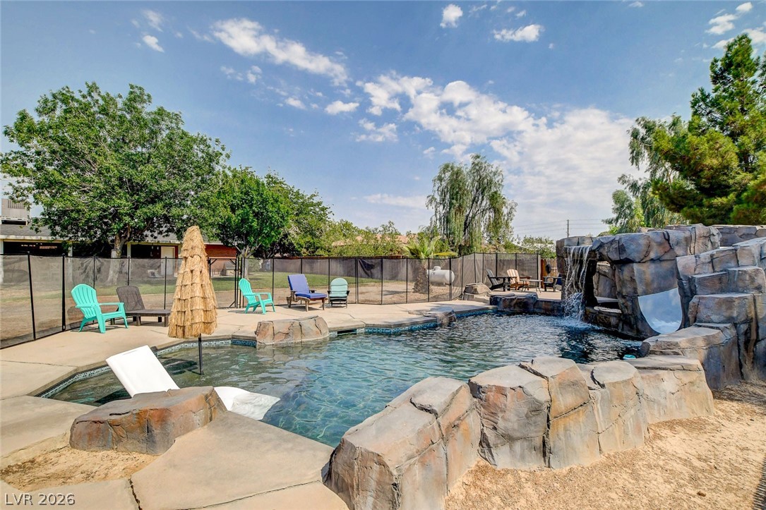 3765 Berkeley Street Logandale, NV 89021 - Photo 82 of 87 An inviting backyard oasis features a freeform pool with a rock waterfall and integrated slide.